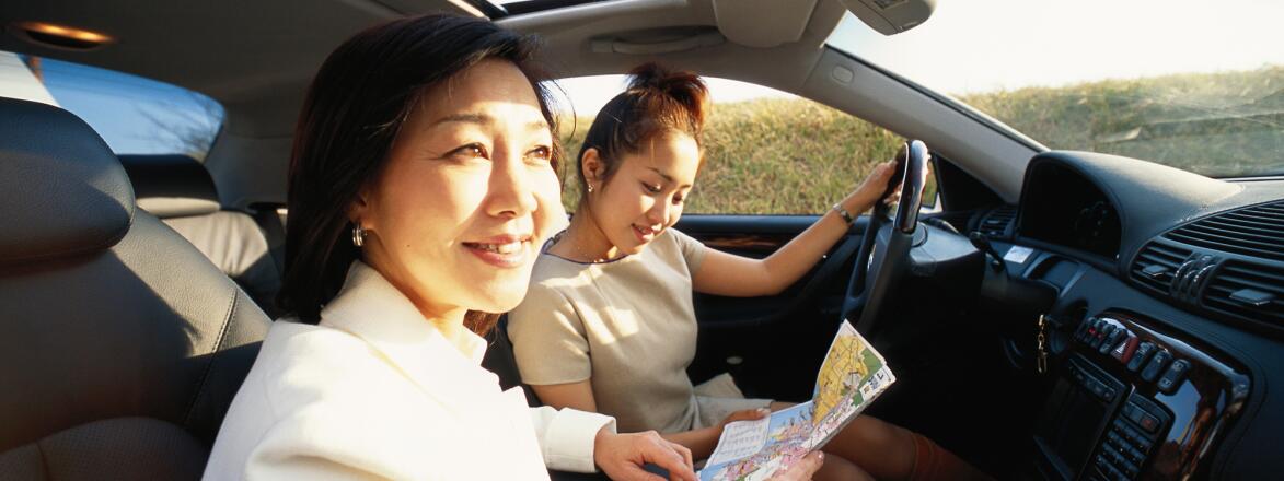 Two women sitting in car, looking at map, elevated view, close up