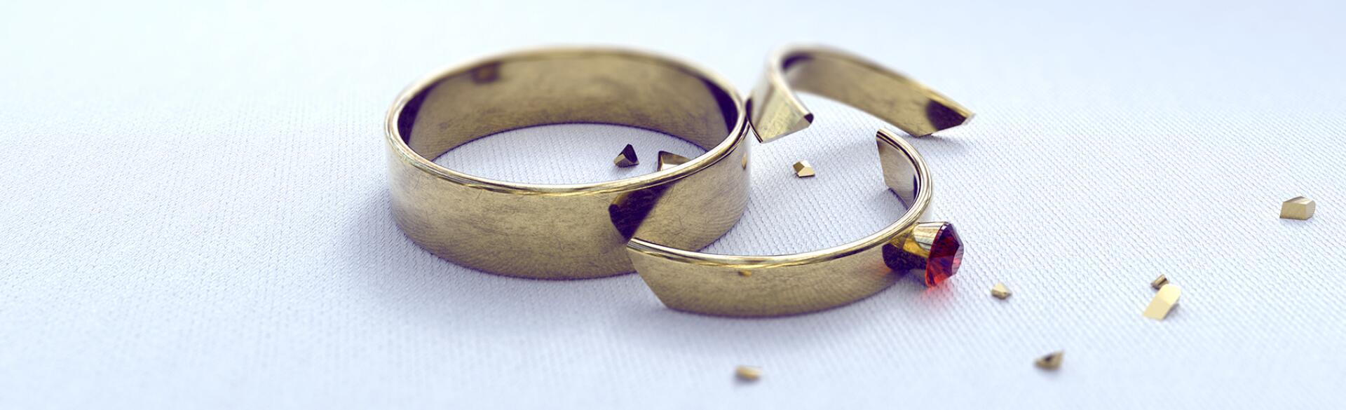 wedding band and cracked engagement ring on a white background