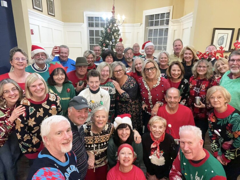 Group of friends from 55+ Community celebrating Christmas in front of a Christmas Tree