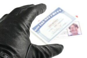 Hand with black glove reaching for Social Security card and driver's license