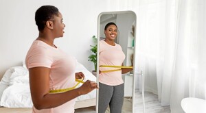 Woman with measuring tape in front of mirror