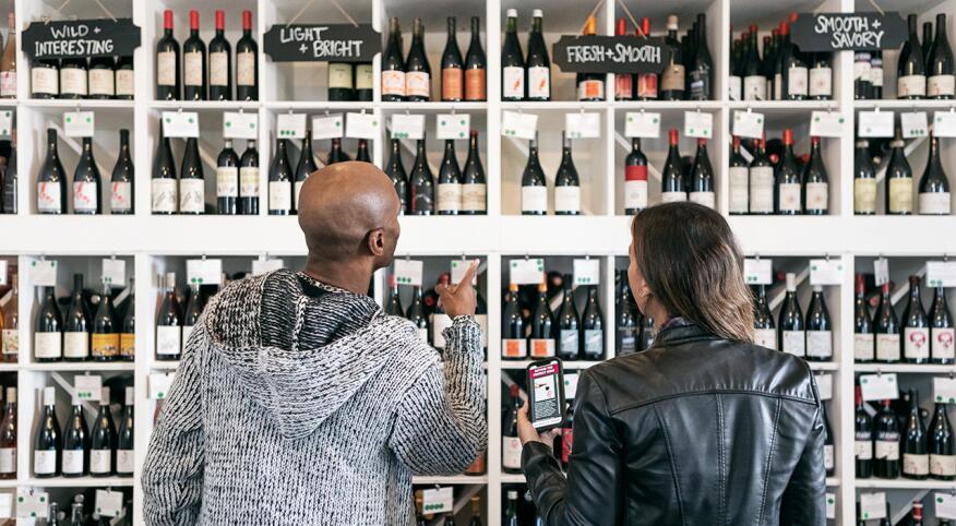 couple looking at many red wines in a store