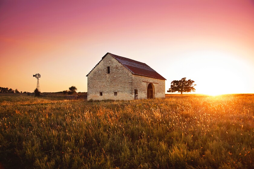 A stone barn stands deglected at sunset. in the Flint Hills of Southern Kansas, USA.