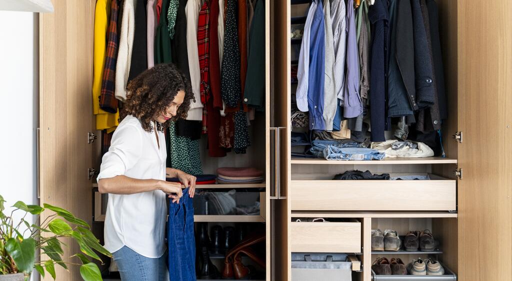 image_of_woman_holding_clothes_in_front_of_closet_GettyImages-1223861343_1800