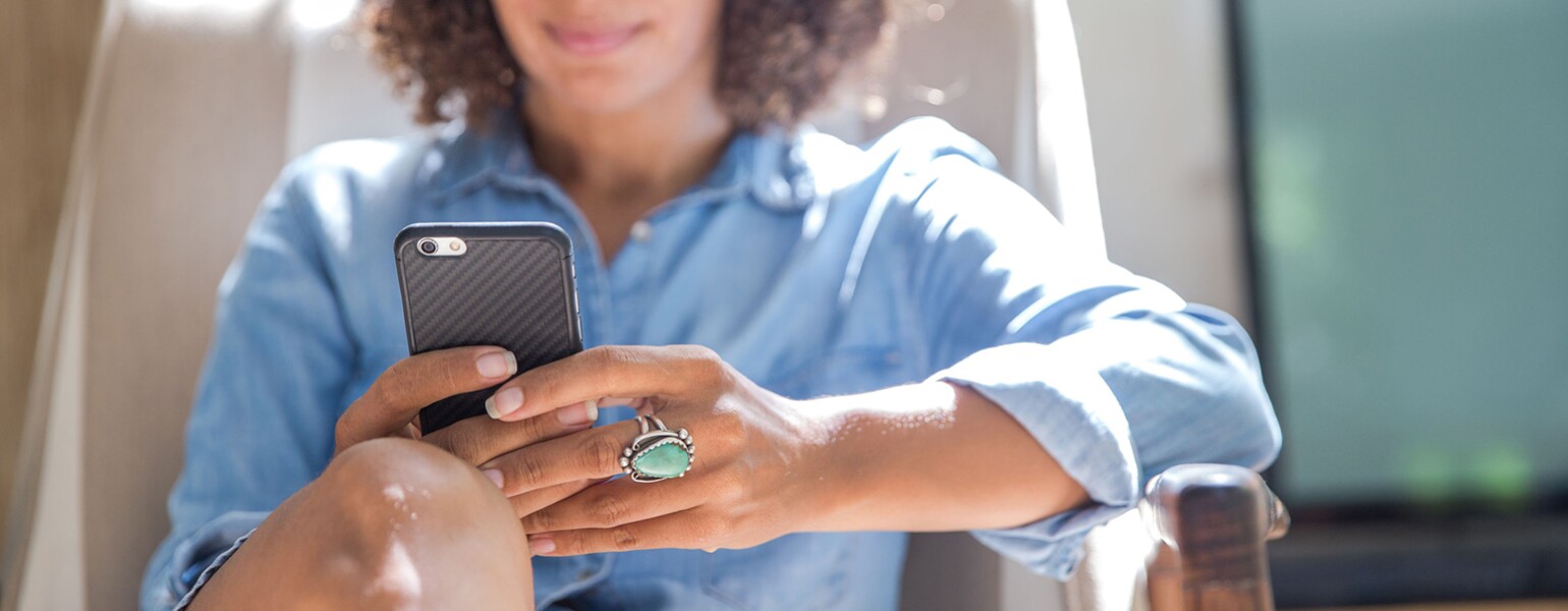 Woman Relaxing At Home While Reading On Her Smartphone
