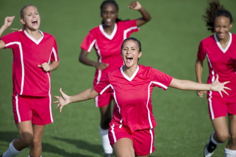 Female soccer players celebrate a goal