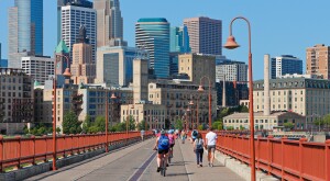 Daytime Minneapolis skyline with people crossing the Stone Arch bridge