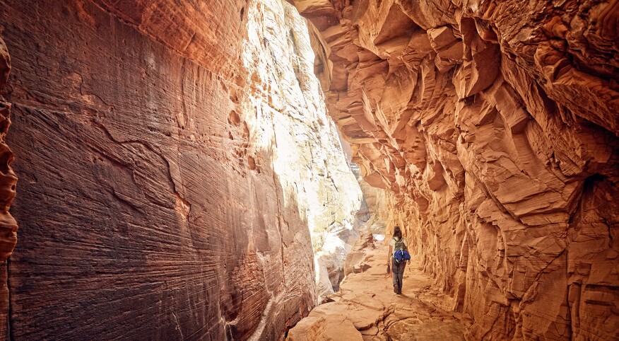 female hiker walking through a cave in Zion national park