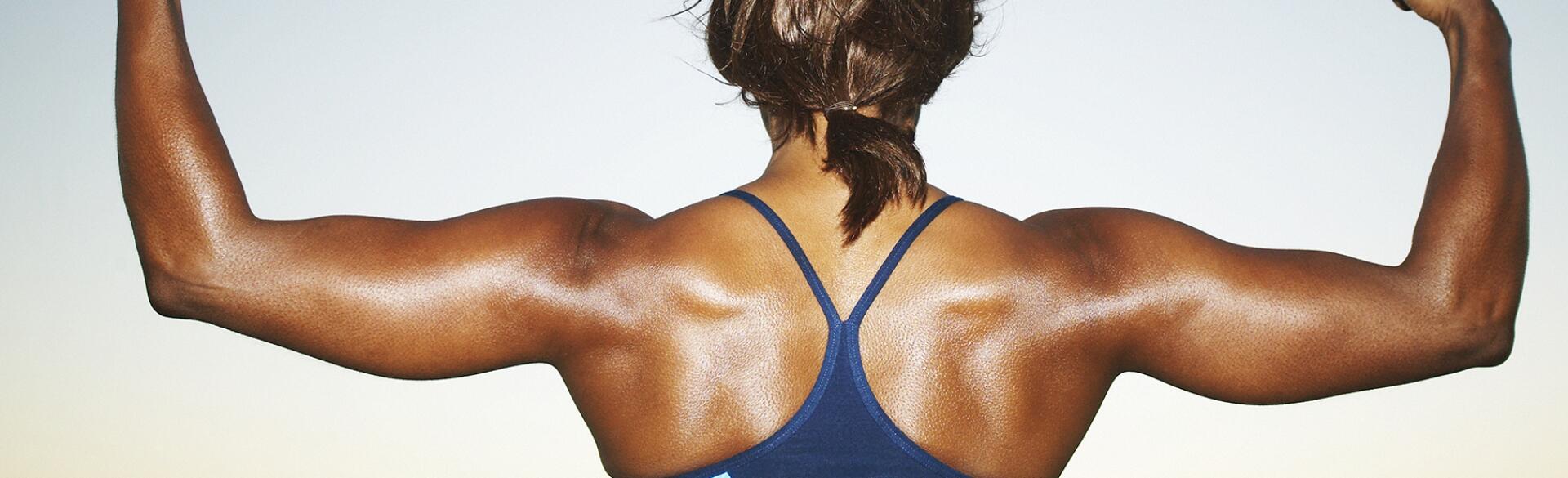 Woman bodybuilder flexing arms, top section, rear view