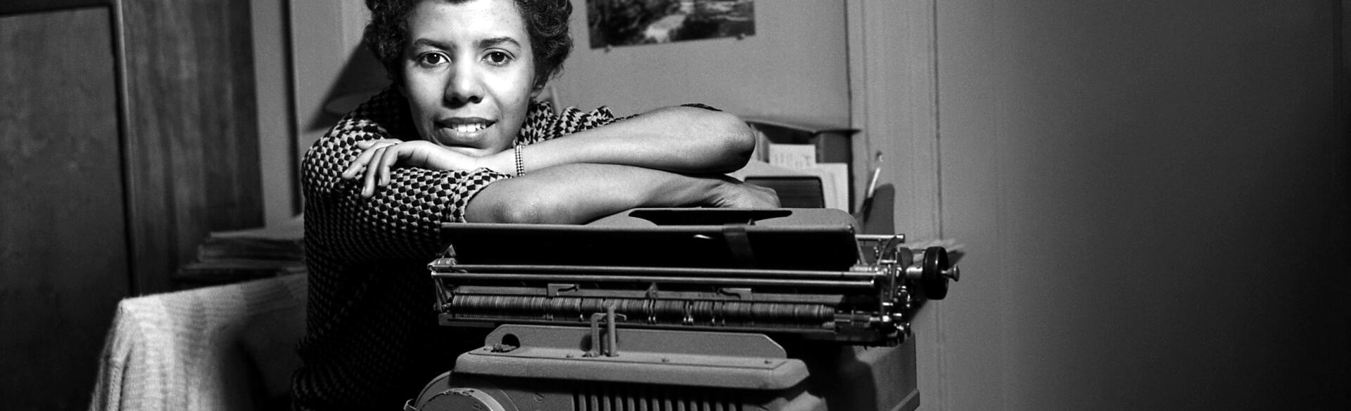 Black and white photo of Lorraine Hansberry leaning on a typewriter.