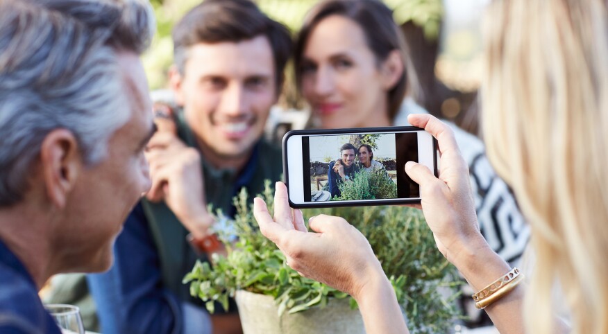 couple taking a photo of another couple on a smartphone