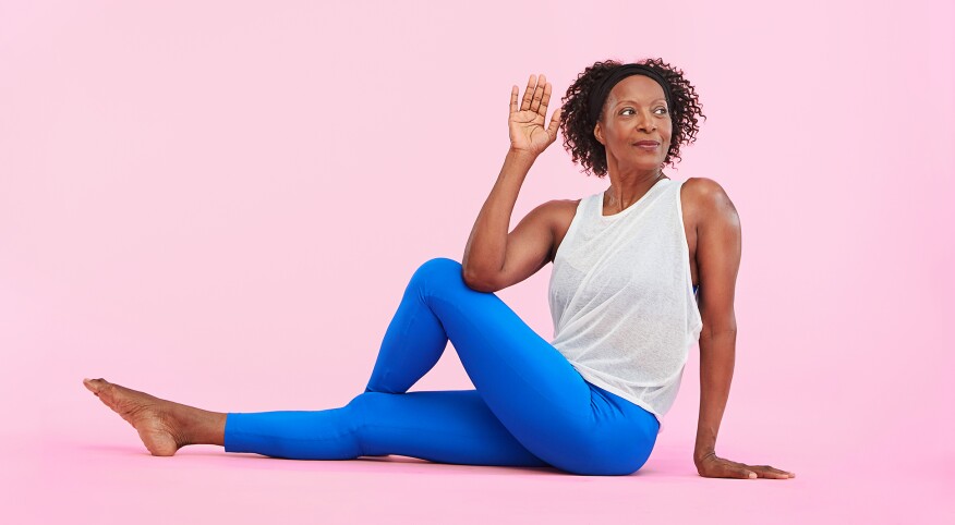 african american woman wearing athletic clothes stretching with yoga on a pink background