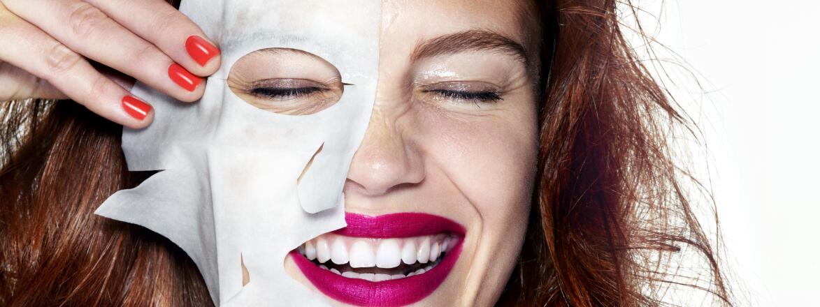 woman smiling with half of a sheet mask on her face