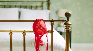 end of bed post with red bra hanging off the edge