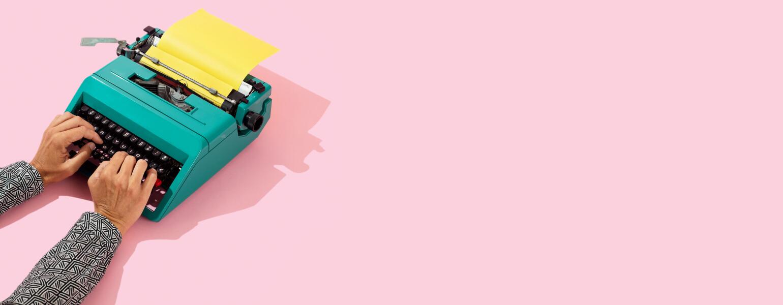 Woman writing on a teal typewriter on a pink background