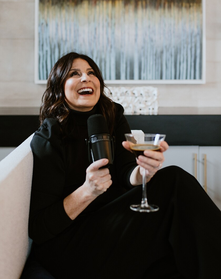 Lori Aronsky, influencer, wearing a pink robe, headband, and drinking a martini