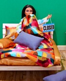 Doll on a bed holding a closed sign