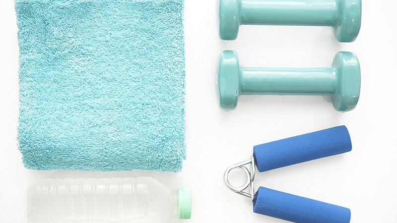 An above view of workout equipment, water bottle and towel on a white background