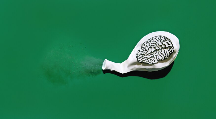 Deflated white balloon blowing out dust with a print of a brain on the balloon.