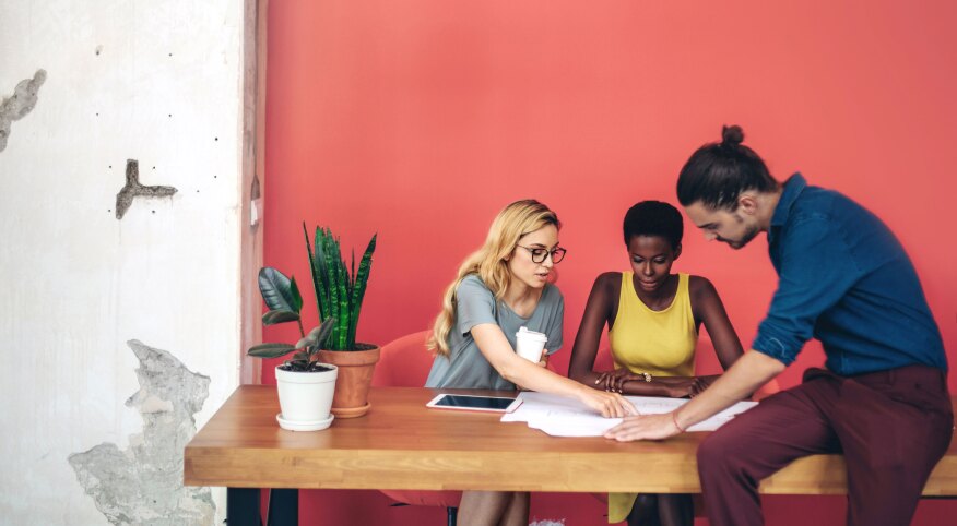 Two women and a man reading paperwork at a desk