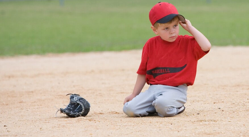 Child sitting down on a baseball field