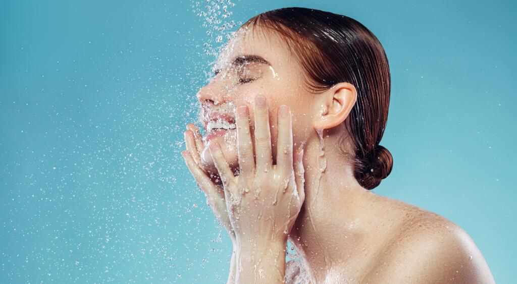 Woman washes her face in front of a blue background