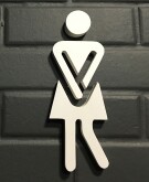 White urinary urgency sign for women on bathroom entrance with black brick wall