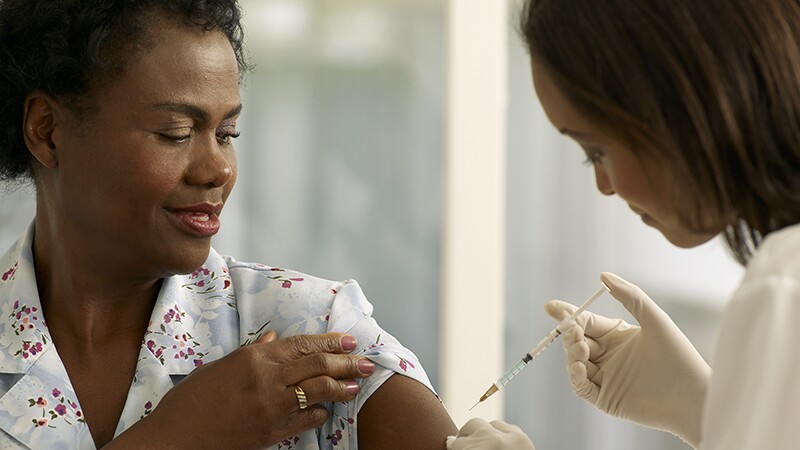 A woman getting a vaccine shot from a female medical professional