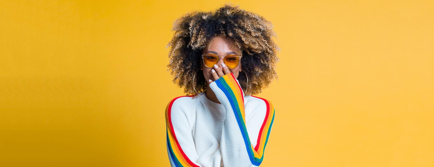 Surprised afro girl standing against yellow background showing her beautiful curls
