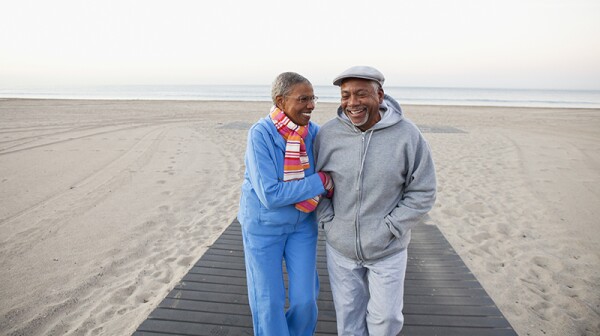 A man and woman smiling and walking together on the beach