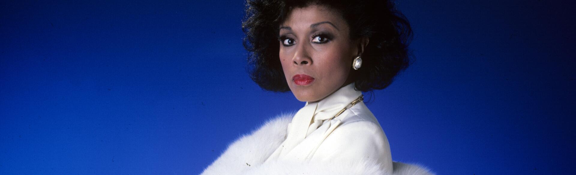 Diahann Carroll on blue background in white suit from TV show Dynasty