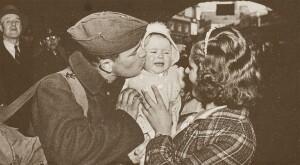 A World War II soldier kisses his baby, held in the arms of his wife, as he says goodbye to his family in London