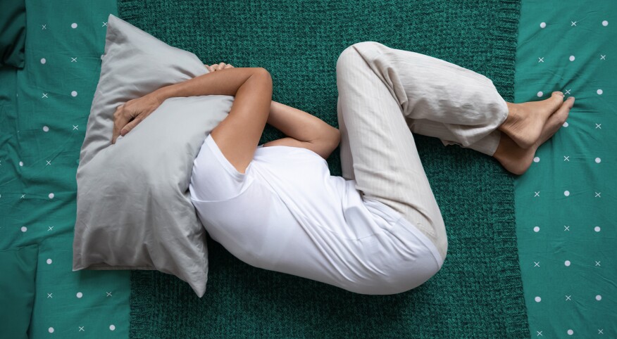 Woman on top of bed with pillow over her head 