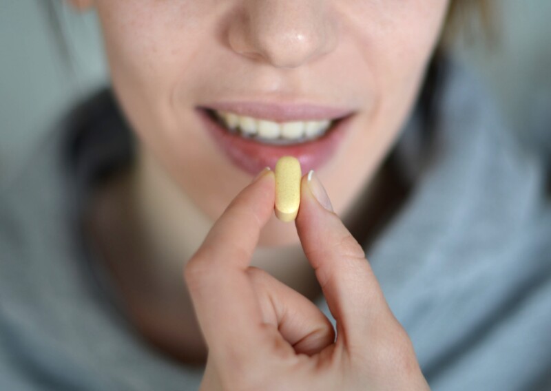 Woman about to swallow capsule