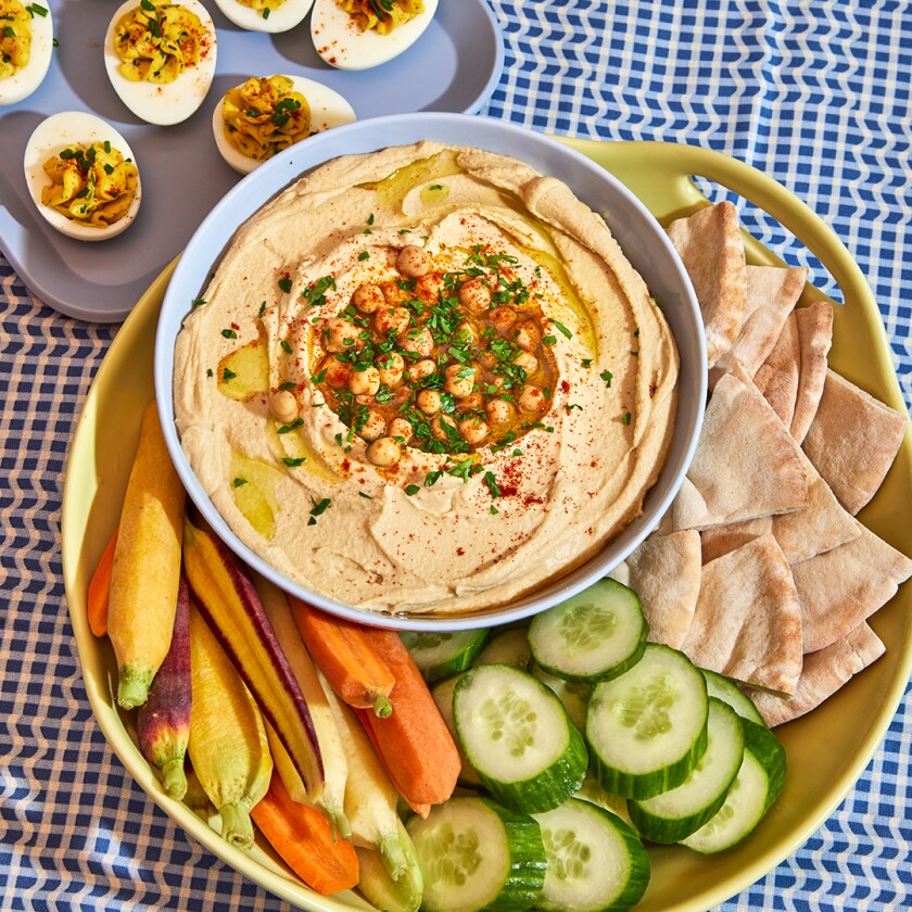 Overhead image of hummus, sliced vegetables and pita