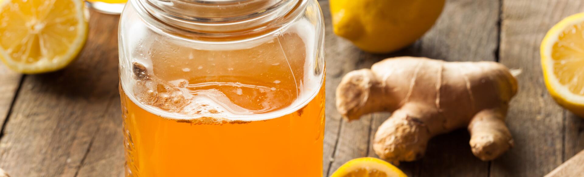 Kombucha in a mason jar surrounded by ginger lemon and oranges