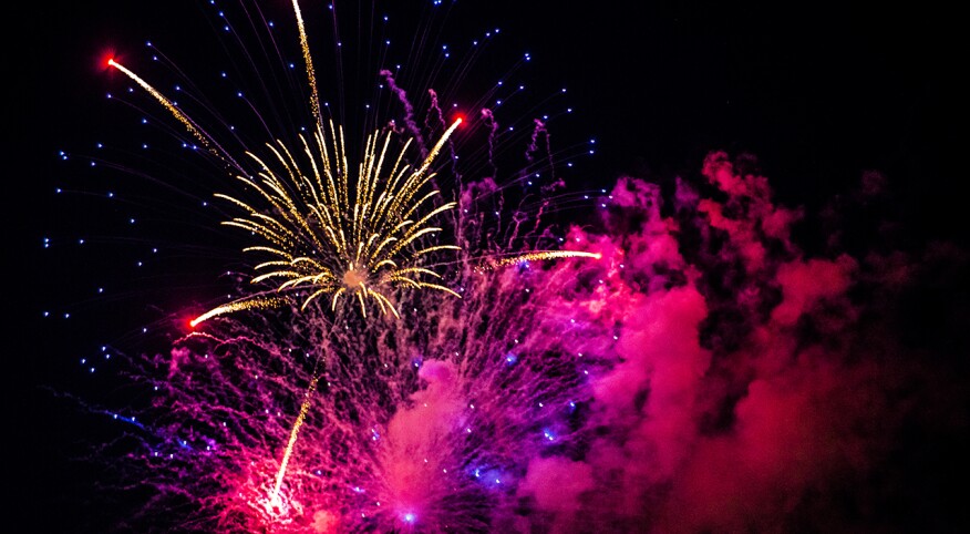 Multicolored burst of fireworks in the night sky with radiant pops of pink, purple, and white