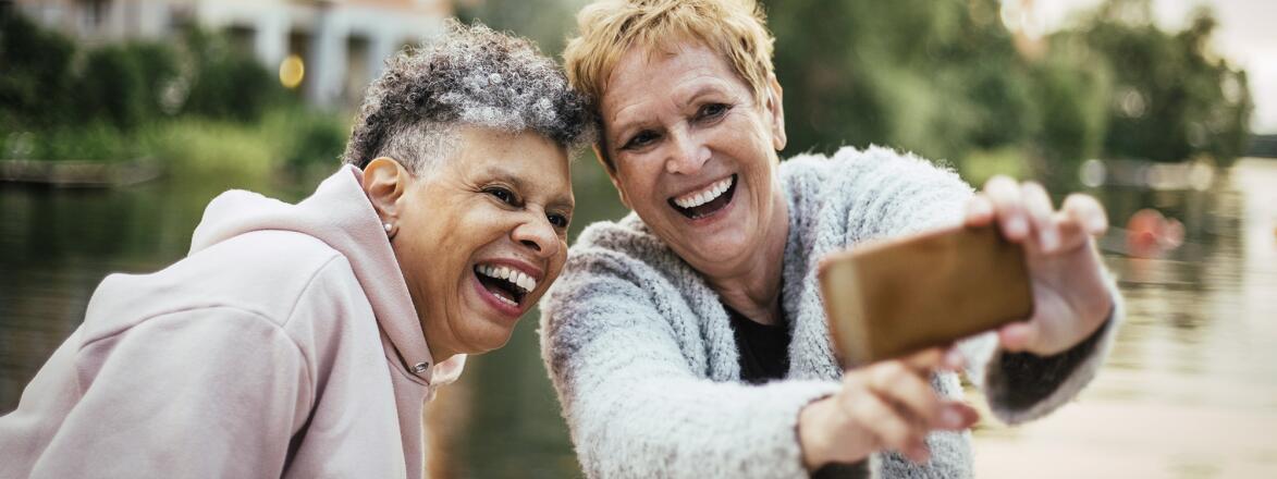 Smiling women enjoying while photographing through smart phone during picnic