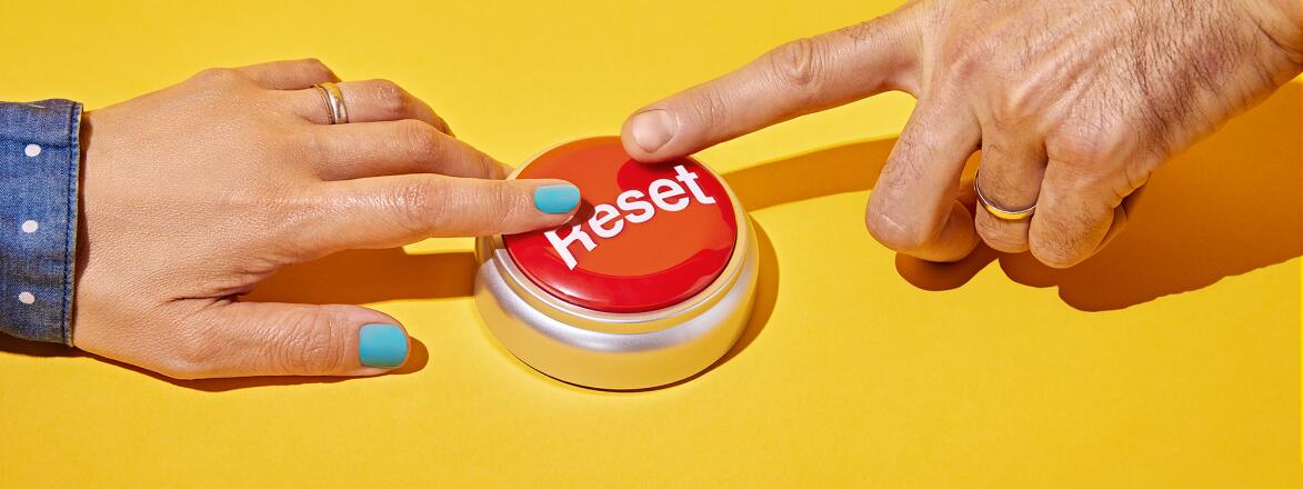 Female and male hand pressing a reset button