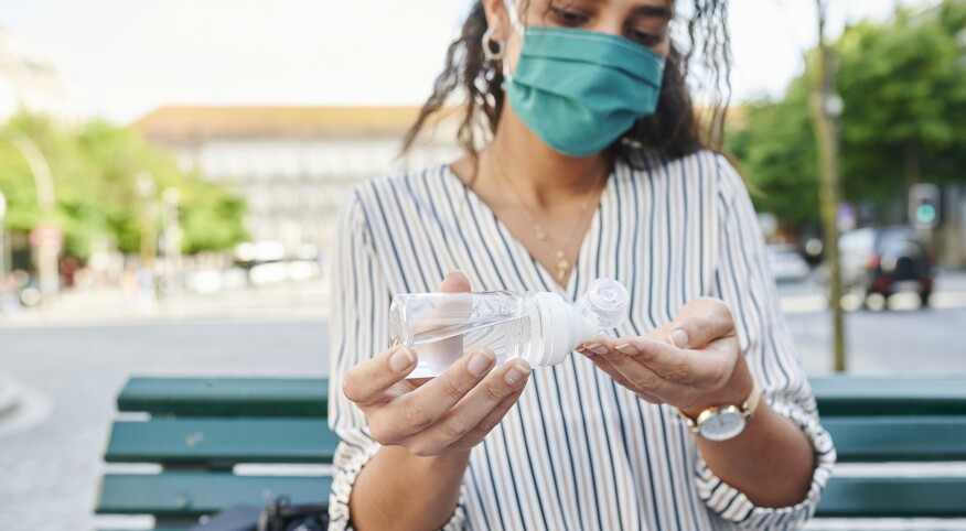 Woman In A Face Mask Putting On Hand Sanitizer