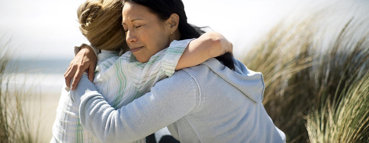 Friends hugging to mourn the loss of one of their parents.