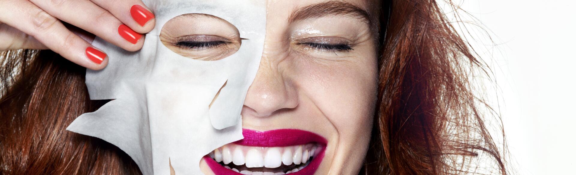 woman smiling with half of a sheet mask on her face