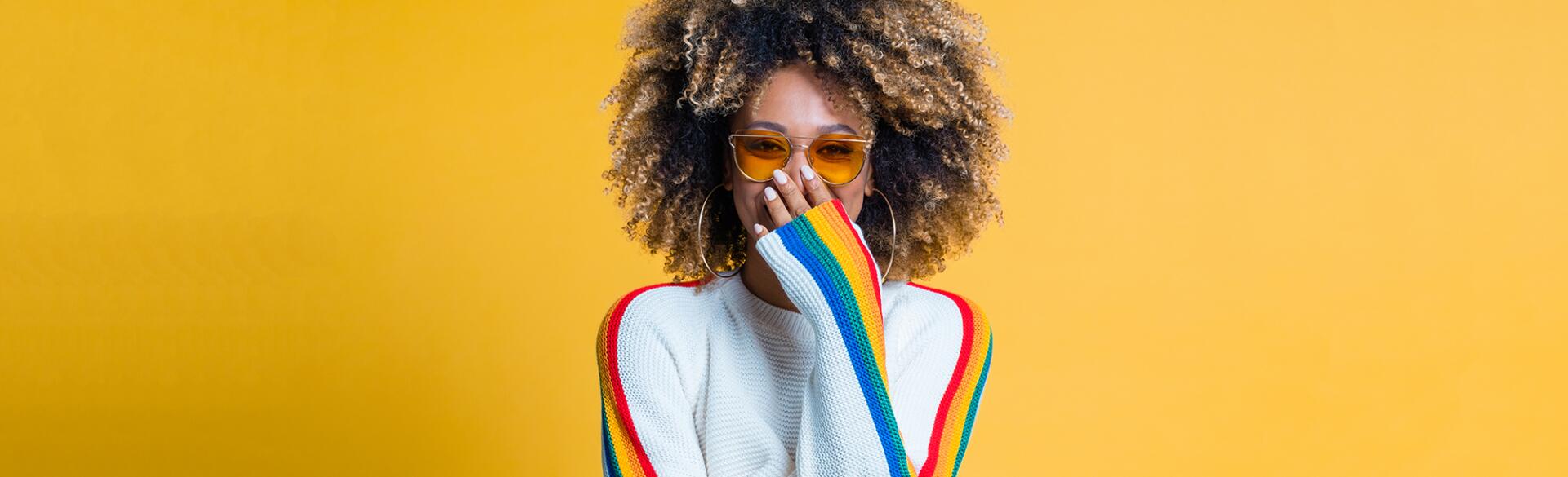 Surprised afro girl standing against yellow background showing her beautiful curls