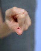 image_of_woman_holding_up_finger_with_one_drop_of_blood_GettyImages-1221079093_v2_1800