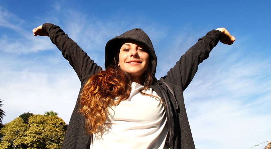 Young woman with arms up in the park