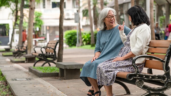 Two women sitting and talking with each other on a park bench