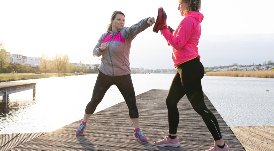 two women practicing self defense near a lake