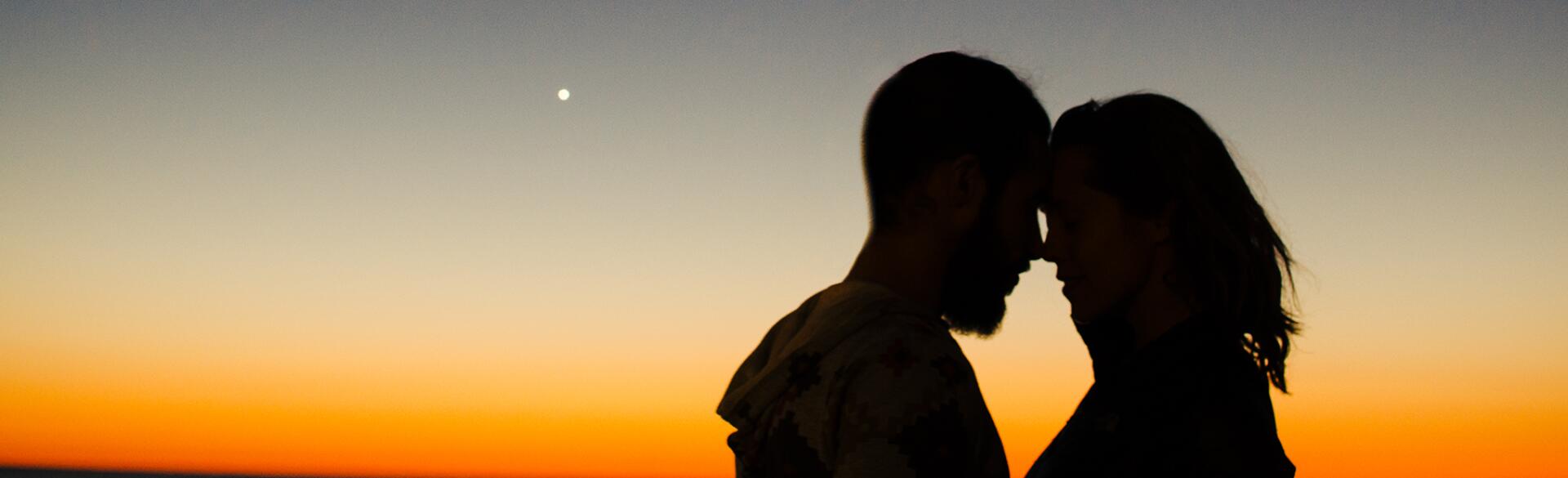 couple embracing in front of sunset