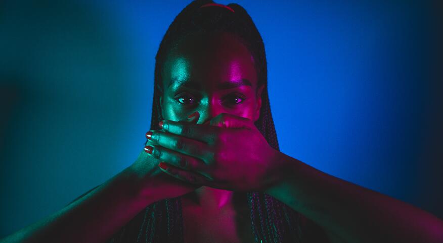 image_of_woman_with_hands_covering_mouth_in_studio_with_blue_lights_GettyImages-1255042836_1800