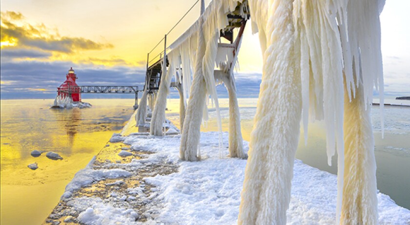 Winter ice buildup on scenic pier and lighthouse.